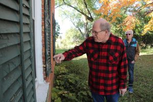 Joe Chase points into the Historic Thompson-Schneider home as Peter Klein looks on