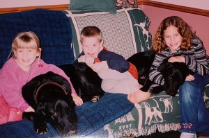 The adopted Klemowits kids sit on a couch holding dogs